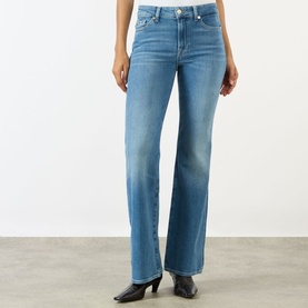 Model wearing Seven Jeans The Leggy Bootcut Jeans in Coastline, mid-rise bootcut with mid wash finish, styled with black heeled boots.