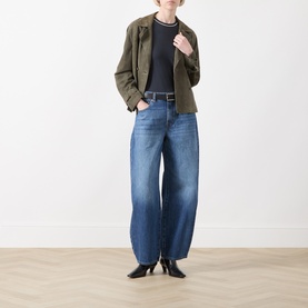 Model wearing Seven Jeans wide-leg jeans in Skyfrost blue denim, styled with an olive jacket and black heeled boots.