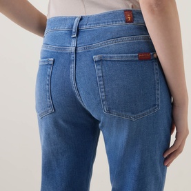 Model wearing Seven Jeans Skinny jeans in Coastline blue denim, rear view showing back pockets and branded tab detail.