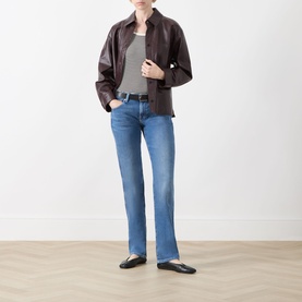 Model wearing Seven Jeans Slim jeans in Coastline blue denim, styled with dark brown leather jacket, grey top and black ballet flats.