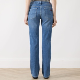 Model wearing Seven Jeans Slim jeans in Coastline blue denim, rear view showing straight leg fit and five-pocket styling.