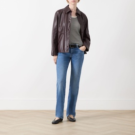Model wearing Seven Jeans Coastline slim jeans in mid-blue wash, styled with a dark brown leather jacket, grey top and black ballet flats.