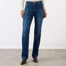Model wearing mid-blue straight-leg jeans with light wash fading, styled with a cream top and black leather boots.