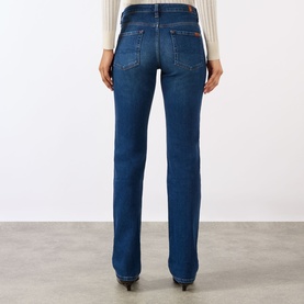 Model wearing mid-blue straight-leg jeans, rear view, styled with a cream top and black heels