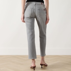 Model wearing grey straight-leg jeans with patch pockets, styled with beige strappy heeled mules, rear view