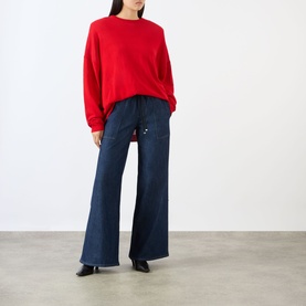 Model wearing Seven Jeans Wide Leg jeans in Halona dark blue denim with drawstring waist, styled with red sweatshirt and black heels.
