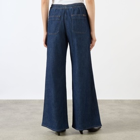 Model wearing Seven Jeans Wide Leg jeans in Halona dark indigo, rear view showing wide-leg silhouette and back pockets