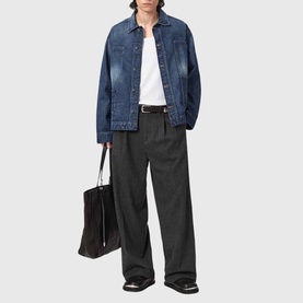 Model wearing All Saints dark indigo denim jacket, styled with white tee, charcoal wide-leg trousers and black tote bag.