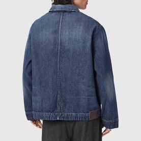 Model wearing All Saints dark indigo denim jacket, rear view, with grey trousers visible at hem