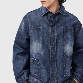 Model wearing All Saints dark indigo denim jacket with contrast stitching, large patch pockets and a worn, faded finish.