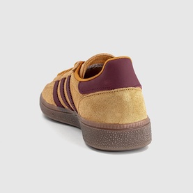 Adidas trainer in preloved yellow and shadow red suede, burgundy heel tab, three-stripe detailing, gum rubber sole, rear angle view.