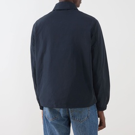 Model wearing Lyle & Scott Eagle Logo Coach Jacket in Dark Navy, rear view, styled with light-wash jeans.