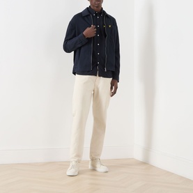 Model wearing Lyle & Scott Eagle Logo Overshirt in Dark Navy with cream trousers and white trainers