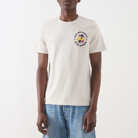 Model wearing Lyle & Scott Logo Nature Graphic T-Shirt in putty with floral chest graphic, styled with light blue jeans.