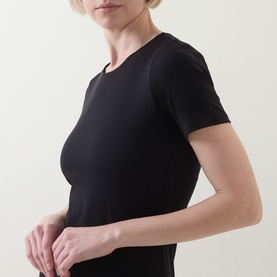 Model wearing Spanx Classic Black fitted short-sleeve dress, cropped torso view showing smooth fabric and crew neckline