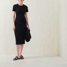 Model wearing Spanx Classic Black short-sleeve ribbed midi dress, styled with brown leather sandals and carrying a black jacket.