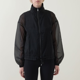 Model wearing Spanx jacket in Very Black with sheer organza sleeves and zip-front, paired with black trousers