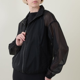 Model wearing Spanx jacket in Very Black with sheer organza sleeves and shoulders, zip-front fastening, cropped fit