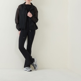 Model wearing Spanx jacket in Very Black with matching black trousers and grey chunky trainers, full-length view