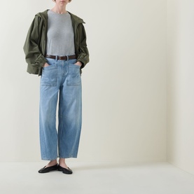 Model wearing Spanx SPANXsupersmooth&trade; Authentic 360 Lightweight Utility Barrel Leg Jeans in Seaside Blue, styled with khaki jacket and black flats.