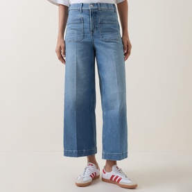 Model wearing wide-leg cropped light blue jeans with patch pockets, styled with white and red trainers
