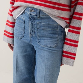 Model wearing light blue wide-leg jeans with large front patch pockets, styled with a grey and red striped knit jumper.