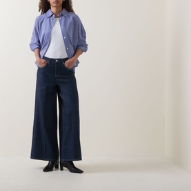 Model wearing Spanx SPANXsupersmooth&reg; Authentic 360 Lightweight Wide-Leg Jeans in Deep Sea with blue stripe shirt and black heeled boots