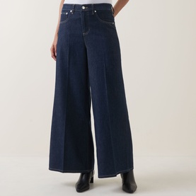 Model wearing Spanx SPANXsupersmooth&reg; Authentic 360 Wide-Leg Jeans in Deep Sea, high-rise, pressed creases, super wide-leg, styled with black ankle