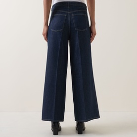 Model wearing Spanx SPANXsupersmooth&reg; Authentic 360 Wide-Leg Jeans in Deep Sea, rear view showing contrast stitching, pressed creases and clean hems