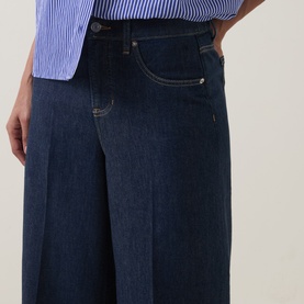Model wearing Spanx SPANXsupersmooth&reg; Authentic 360 Wide-Leg Jeans in Deep Sea, showing five-pocket styling, contrast stitching and pressed creases.