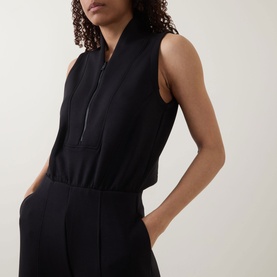 Model wearing Spanx AirEssentials&reg; Half-Zip Jumpsuit in Very Black, showing sleeveless shawl collar, half-zip detail and fitted waist.