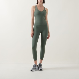 Model wearing Spanx SPANXshape&trade; Booty Boost&reg; 7/8 Leggings in Eucalyptus with matching green vest top and grey trainers