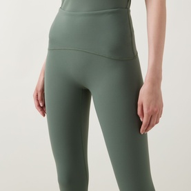 Model wearing Spanx SPANXshape&trade; Booty Boost&reg; 7/8 Leggings in Eucalyptus, showing contoured waistband detail, cropped view.