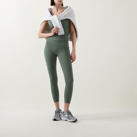 Model wearing Spanx SPANXshape&trade; Booty Boost&reg; 7/8 Leggings in Eucalyptus, styled with a white sweatshirt and grey trainers.