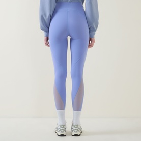 Model wearing Spanx SPANXshape&reg; BodyLine Sheerious Leggings in Hyacinth with mesh panel accents, styled with a blue sweatshirt and white trainers.