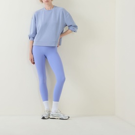 Model wearing Spanx SPANXshape&reg; BodyLine Sheerious Leggings in Hyacinth, styled with matching blue sweatshirt and white trainers.