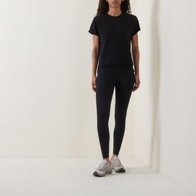 Model wearing black fitted leggings styled with a black short-sleeve T-shirt and grey chunky trainers