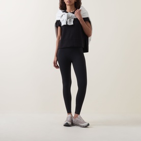 Model wearing black leggings and a black and white top, styled with grey trainers
