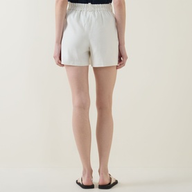 Model wearing Spanx SPANXsupersmooth&reg; EasyBreezy Shorts in Ivory, cotton-linen blend, shown from behind with black slider sandals.