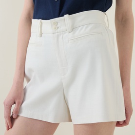 Model wearing Spanx SPANXsupersmooth&reg; EasyBreezy Shorts in ivory with double button fastening and belt loops, styled with a navy top.
