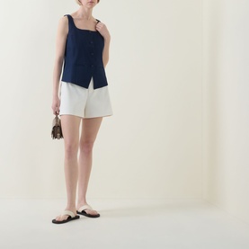 Model wearing Spanx SPANXsupersmooth&reg; EasyBreezy Shorts in Ivory, styled with a navy sleeveless top and black flat sandals