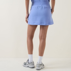 Model wearing Spanx BoostUp Skort 15" in Hyacinth, rear view. Styled with white socks and grey trainers.