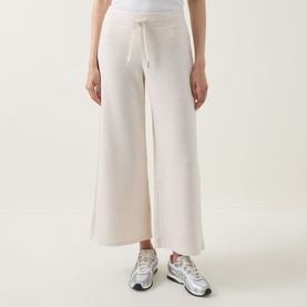 Model wearing Spanx AirEssentials Wide Leg Track Pants Petite in Oatmeal Heather, wide-cut silhouette with drawstring waist, styled with silver