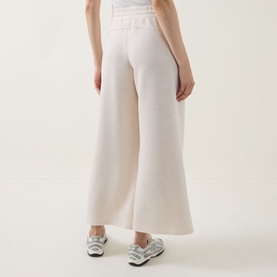 Model wearing Spanx AirEssentials Wide Leg Track Pants Petite in Oatmeal Heather, showing wide-cut legs and elasticated waistband, styled with white