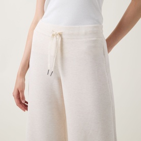 Model wearing Spanx AirEssentials Wide Leg Track Pants Petite in Oatmeal Heather, showing drawstring waist and wide-cut leg detail.