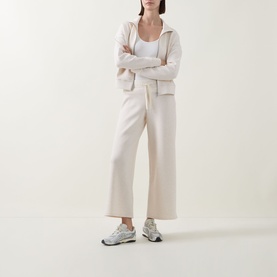 Model wearing Spanx AirEssentials Wide Leg Track Pants Petite in Oatmeal Heather, styled with matching zip hoodie and grey trainers.