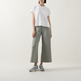 Model wearing Spanx AirEssentials Wide Leg Track Pants Petite in Sage Heather, wide-cut cropped legs, styled with white tee and grey trainers.