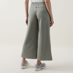 Model wearing Spanx AirEssentials Wide Leg Track Pants Petite in Sage Heather, showing wide-cut legs and elasticated waistband from behind, styled