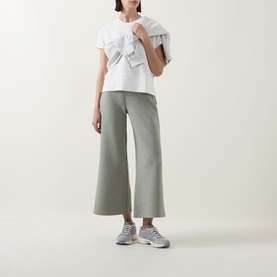 Model wearing Spanx AirEssentials&reg; Wide Leg Track Pants Petite in Sage Heather, wide-cut cropped style, paired with white ruffle top and grey