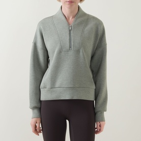 Model wearing Spanx AirEssentials&reg; Half-Zip Sweatshirt in Sage Heather with half-zip, seam detail and ribbed trims, styled with dark leggings